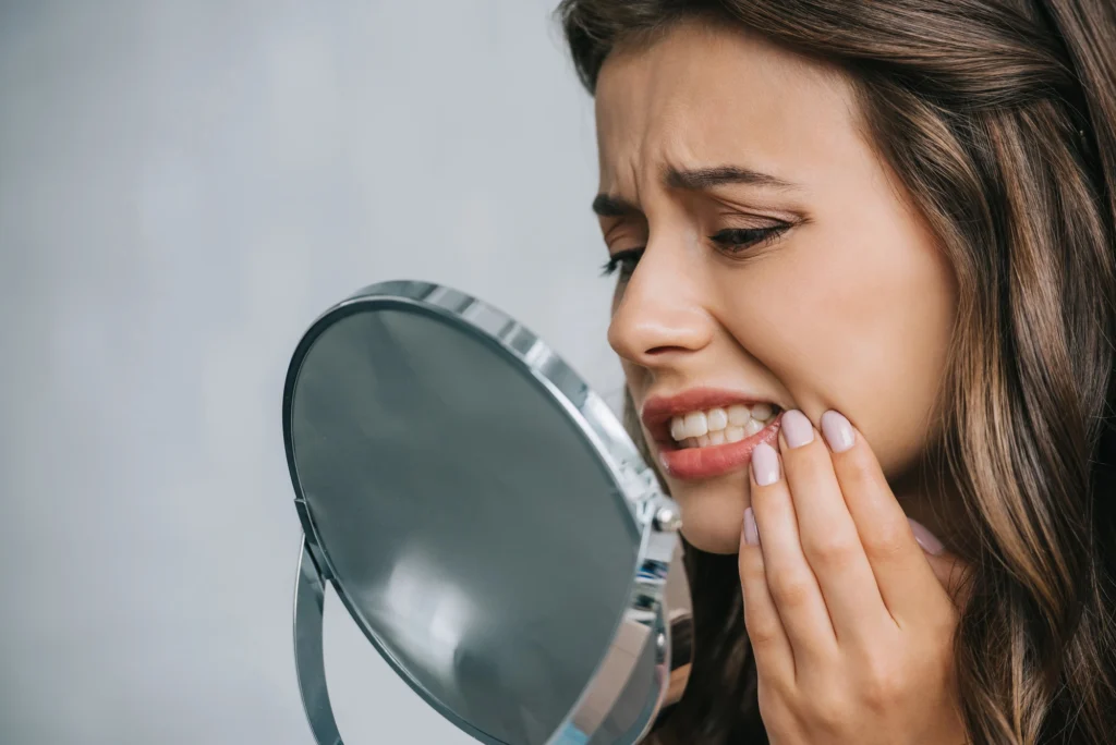 woman holding face in pain before getting tooth fillings in Park Road, NC