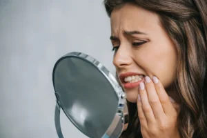 woman holding face in pain before getting tooth fillings in Park Road, NC